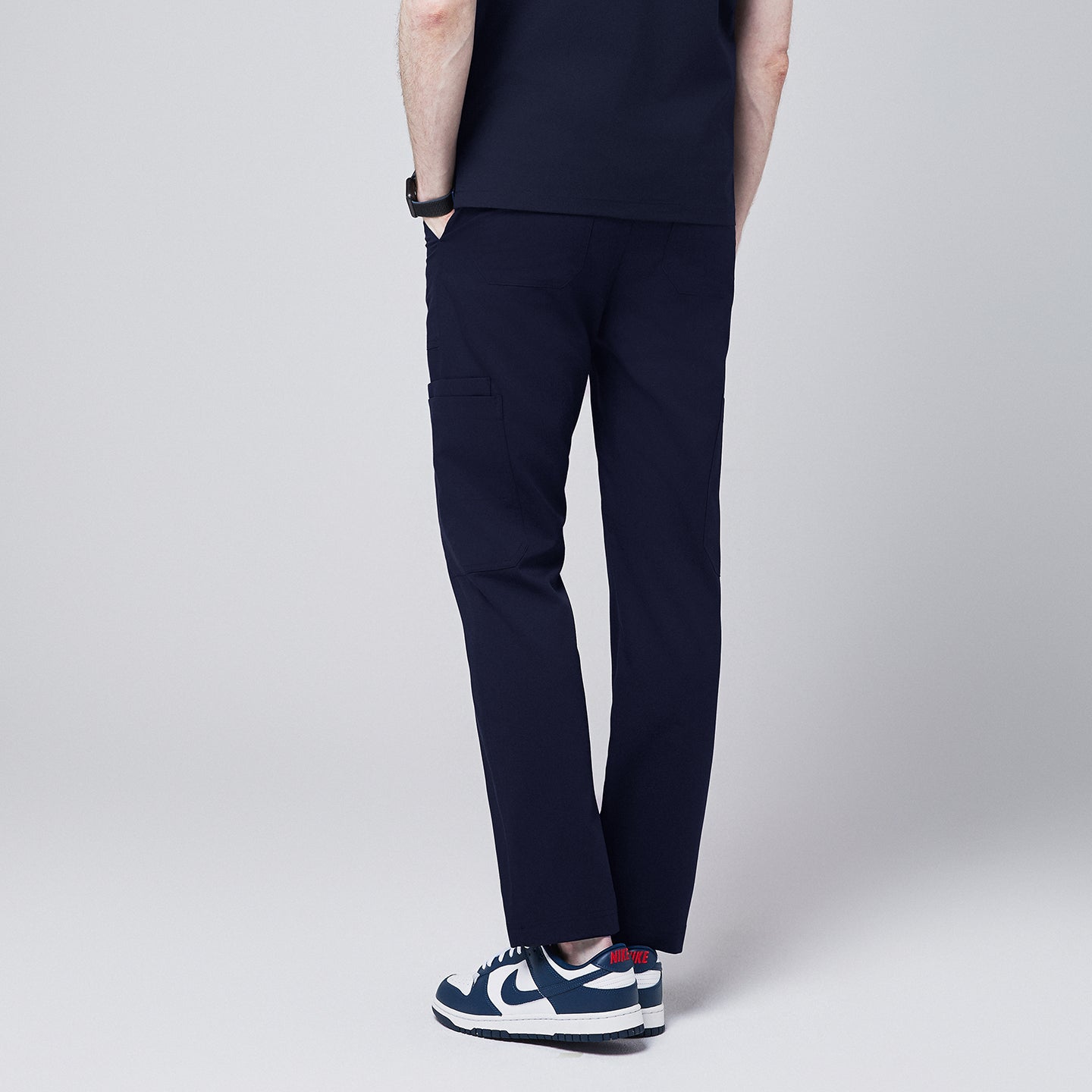 Image of Navy blue 8-pocket straight scrub pants viewed from the back, paired with white and blue sneakers,Eco Navy