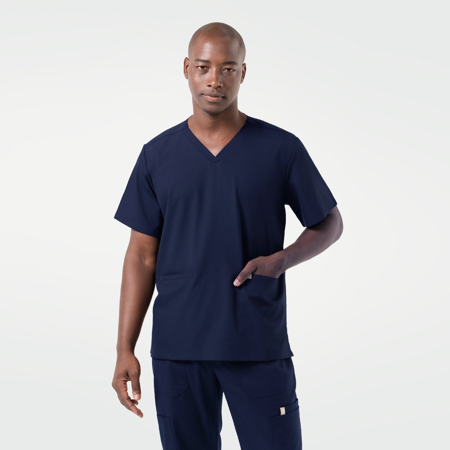 Image of Wearing an Eco Navy scrub set, the male model stands facing forward with one hand placed in the front pocket, presenting a clean and professional look.