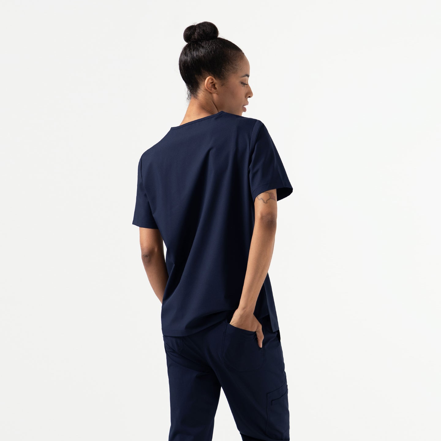 Image of Back view of the Eco Navy Double Pocket Scrub Top worn with matching scrub pants.