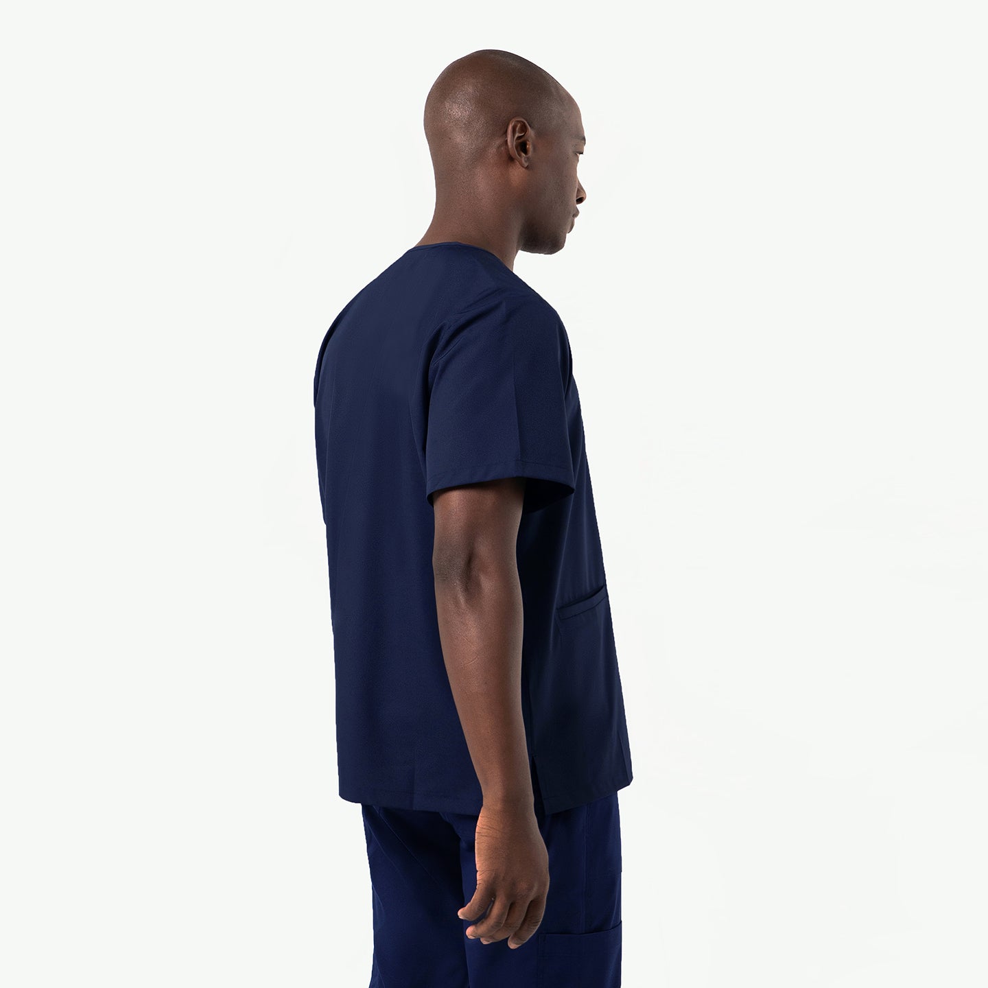Image of Side-profile view of a man wearing an Eco-Navy double-pocket scrub top, highlighting the clean sleeve structure, relaxed V-neck fit, and smooth, durable fabric that drapes naturally while offering a modern, professional silhouette.