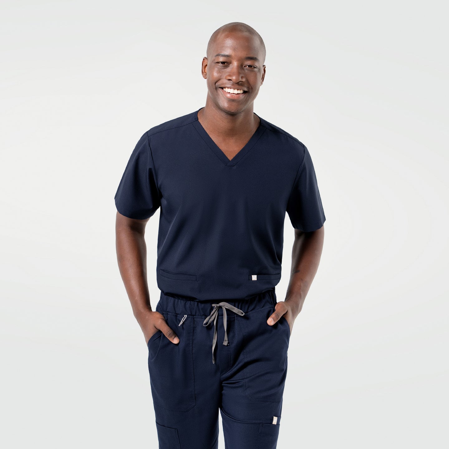 Image of Dressed in the Admiral Blue Double Pocket Scrub Top, the model poses confidently with a relaxed expression.
