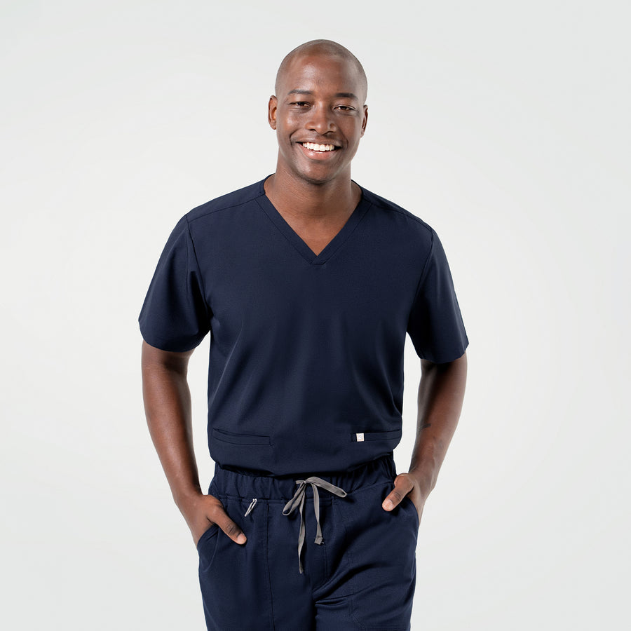 Dressed in the Admiral Blue Double Pocket Scrub Top, the model poses confidently with a relaxed expression.