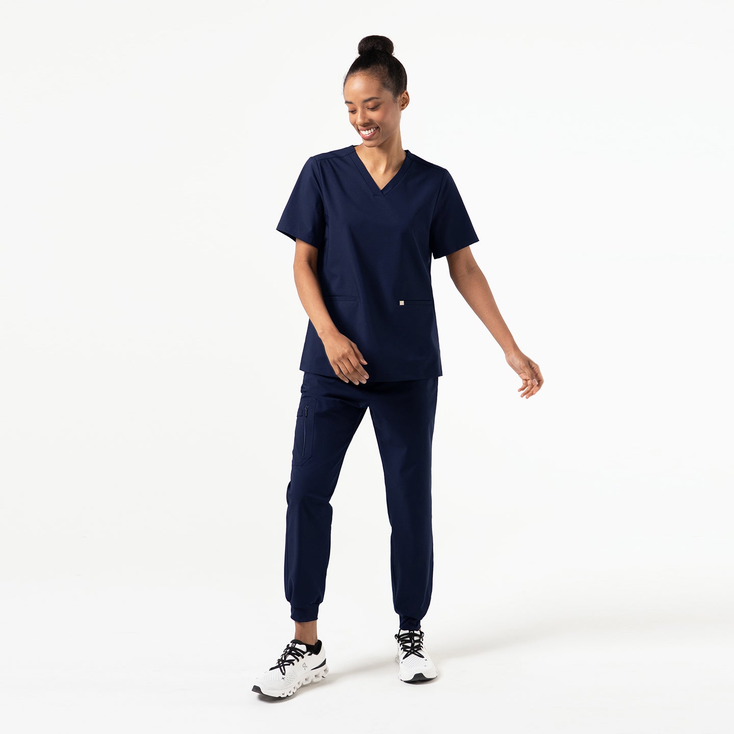 Image of Front view of a model wearing the Eco Navy Double Pocket Scrub Top with matching jogger pants.
