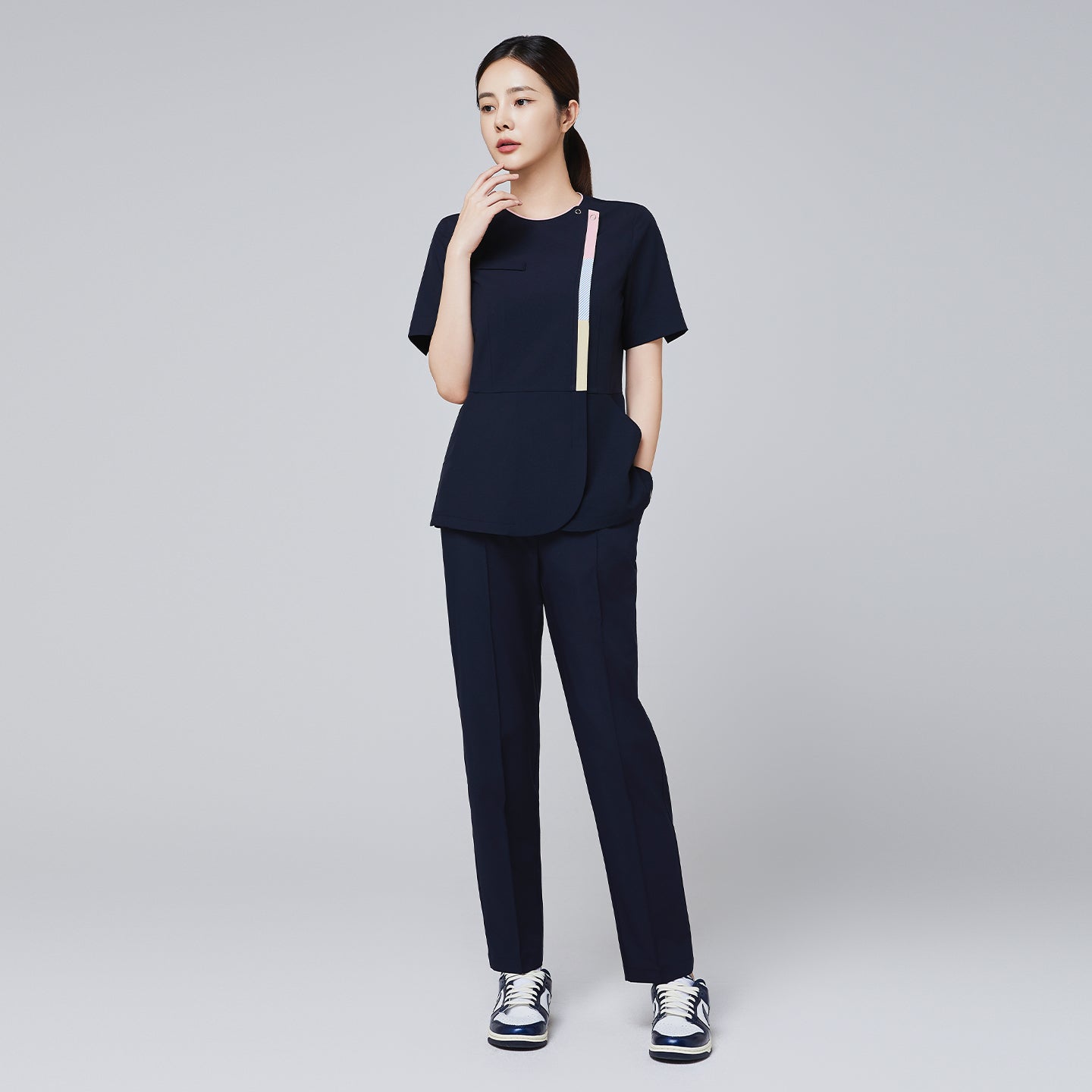 Image of Eco navy scrub set with short-sleeve top featuring colorful stripe detail and matching banding pants, paired with navy and white sneakers,Eco Navy