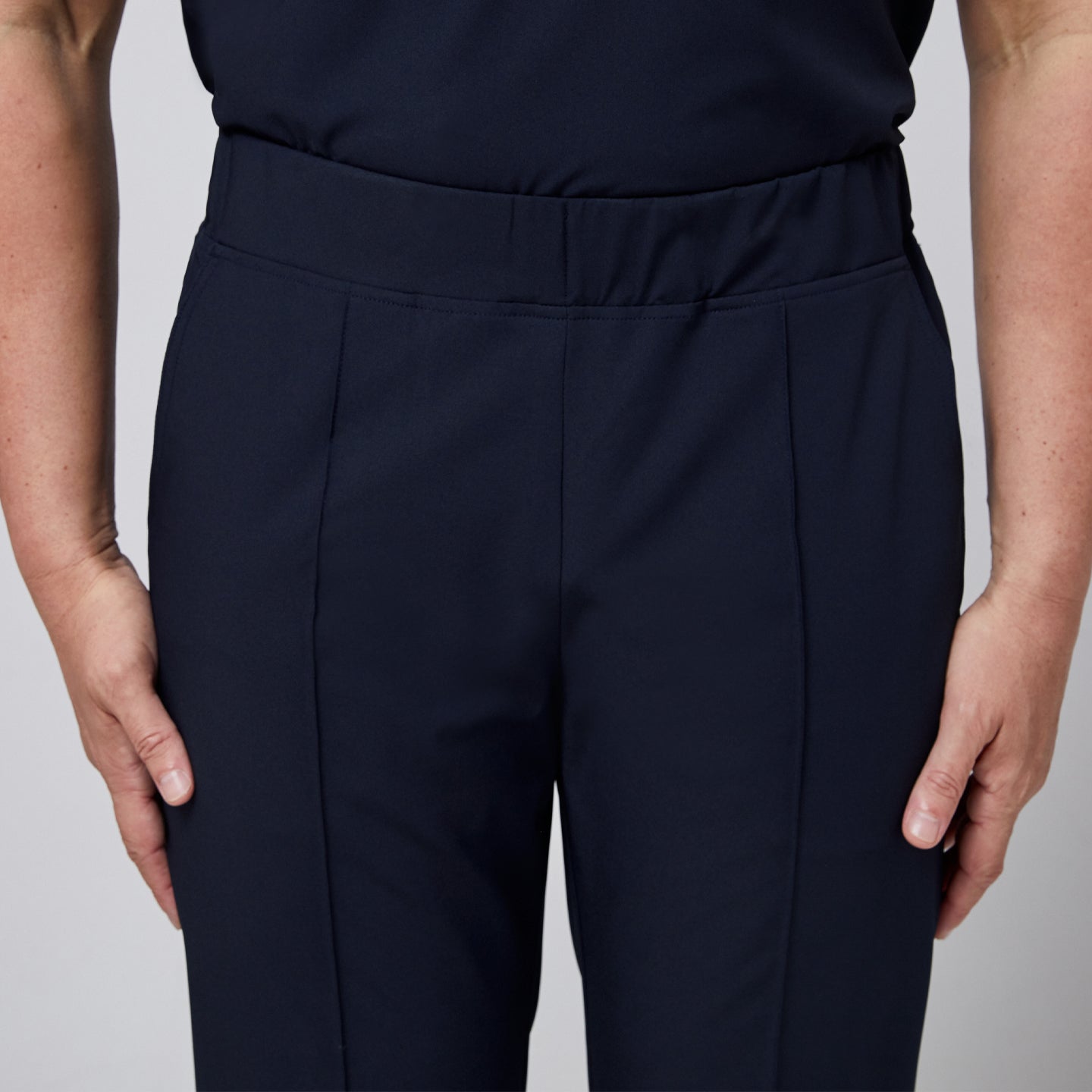 Image of Close-up view of the waistband and front stitching details on navy blue M-line banding scrub pants,Eco Navy