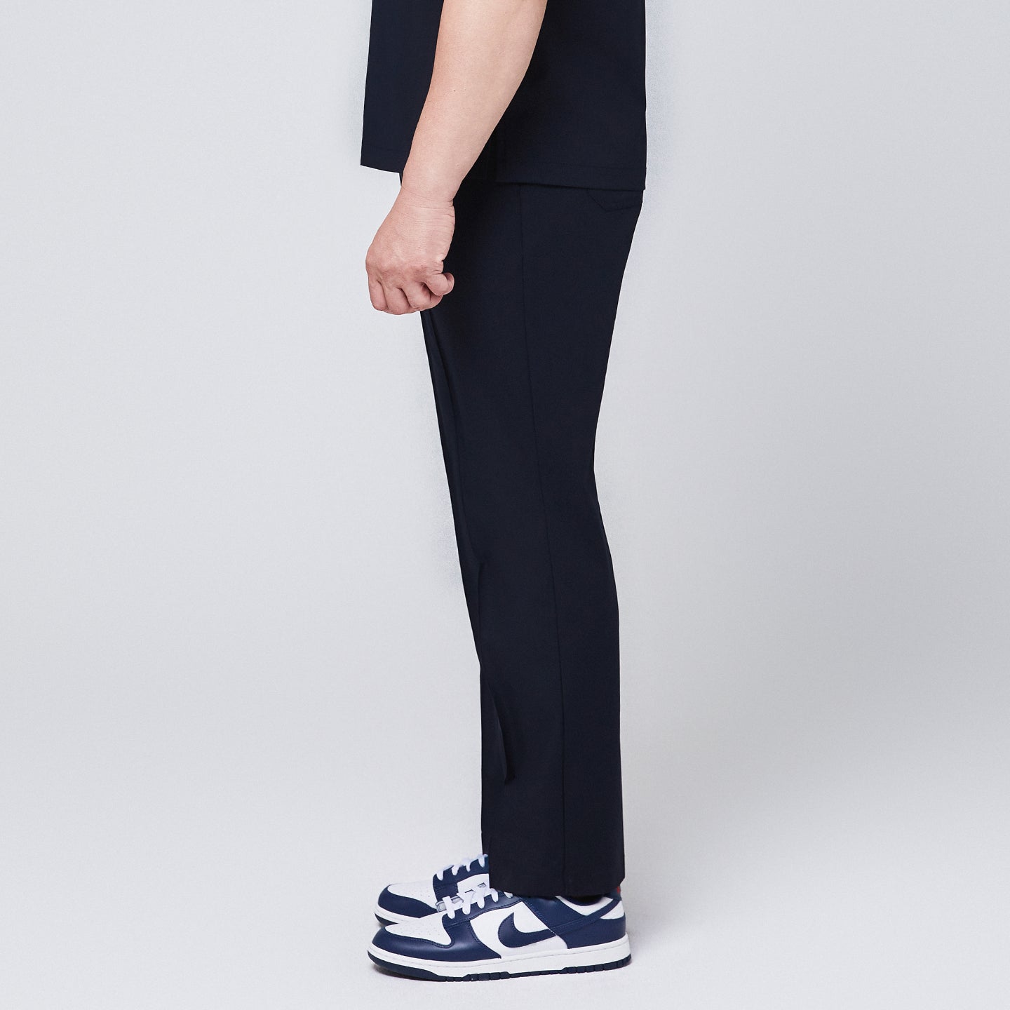 Image of Side view of navy blue M-line banding scrub pants paired with white and blue sneakers,Eco Navy