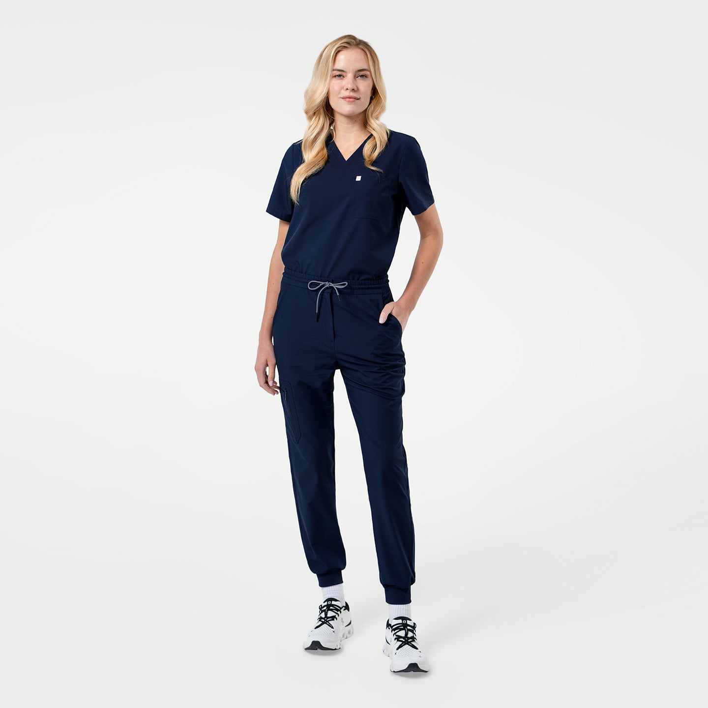 Model wearing the Eco-Navy Zenir single-pocket scrub top paired with matching jogger pants, showcasing its clean V-neckline, lightweight fabric, and streamlined, professional fit.