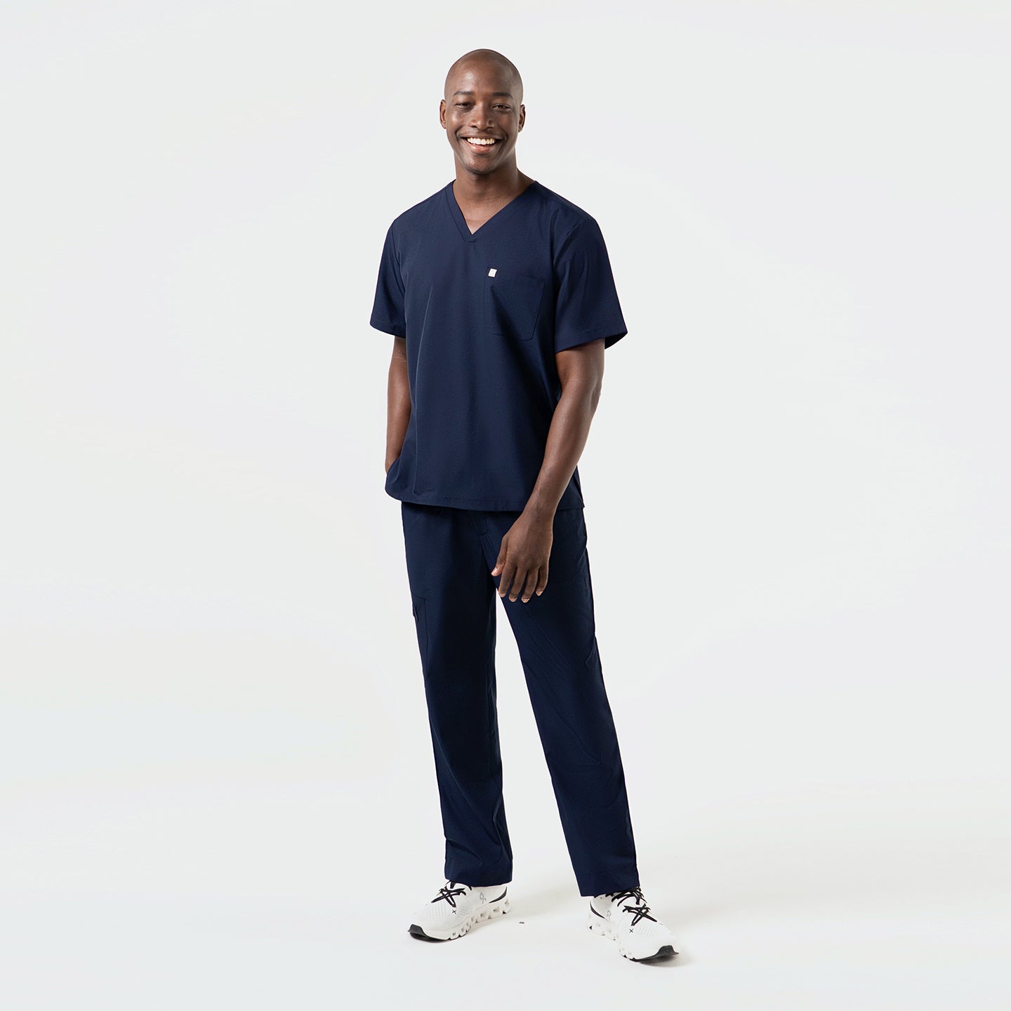 Image of Full-body view of a model in an Eco-Navy single-pocket scrub top and matching pants, highlighting the streamlined V-neck silhouette and lightweight performance fabric.