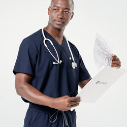 Image of Holding a Zenir clipboard and documents, the male model wears an Eco Navy scrub set with a stethoscope around his neck, looking to the side with a focused expression.