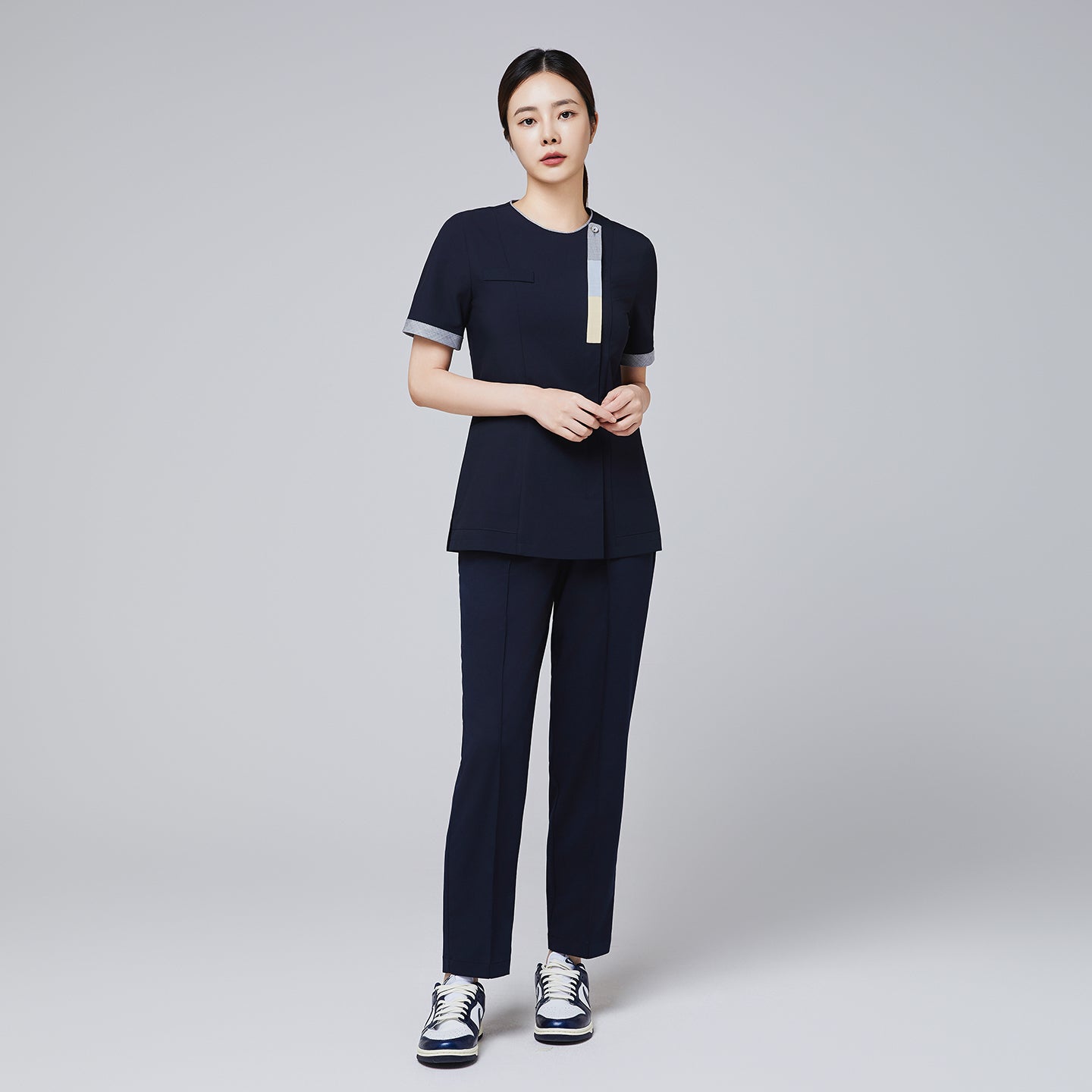 Image of Full-length shot of TUL Women's Premium Banding Pants in Eco Navy, paired with a coordinating scrub top for a cohesive uniform look.