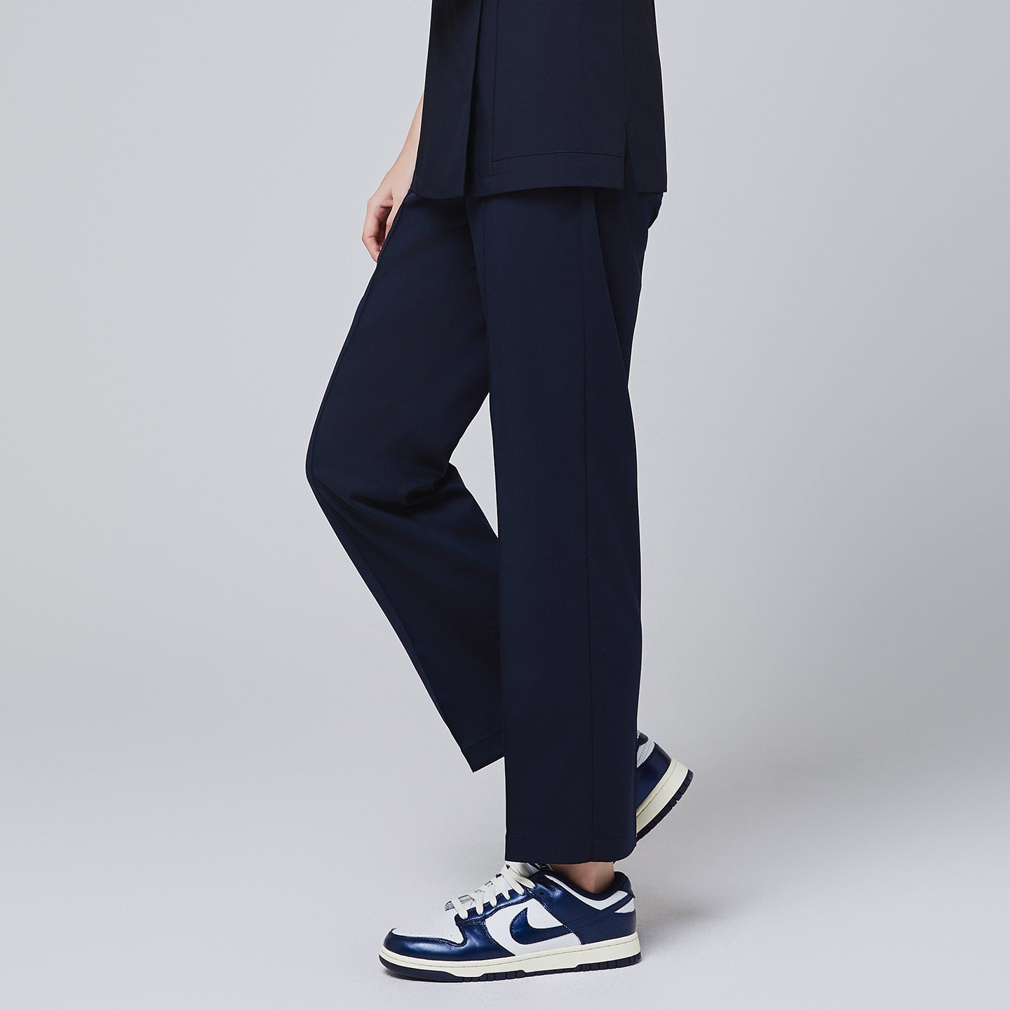 Image of Model walking in TUL Women's Premium Banding Pants in Eco Navy, showcasing the flexible, straight-leg design and durable fabric.