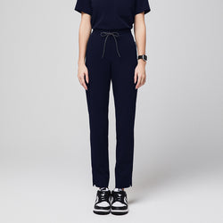 Image of Front view of Zenir Women's Zipper Pocket Split Hem Scrub Pants in Eco Navy on a model, highlighting the clean, straight-leg cut, functional zipper pockets, and the dynamic split hem design.
