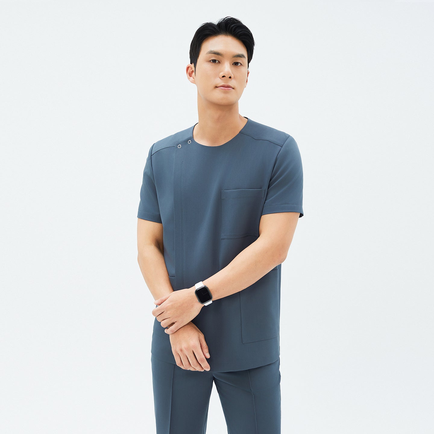 Image of Model wearing TUL DS-190 Haze Gray scrub top, showcasing a round snap neckline, front zipper, and a chest pocket.