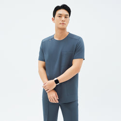 Image of Model wearing TUL DS-190 Haze Gray scrub top, showcasing a round snap neckline, front zipper, and a chest pocket.