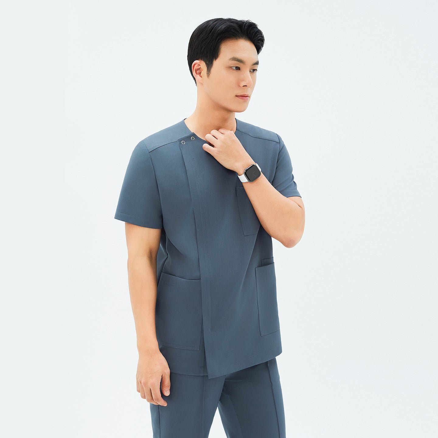 Side angle of TUL DS-190 Haze Gray scrub top, highlighting spacious front pockets and a tailored fit.