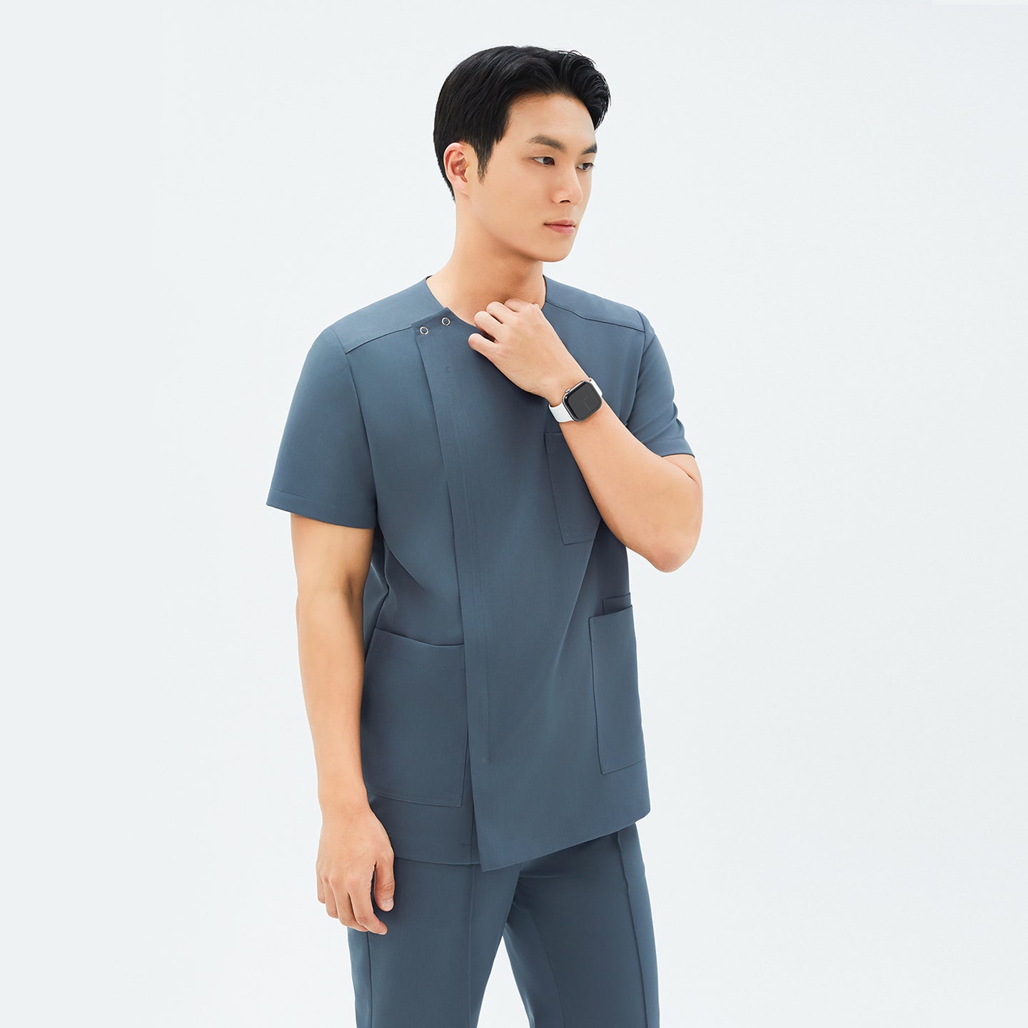 Image of Side angle of TUL DS-190 Haze Gray scrub top, highlighting spacious front pockets and a tailored fit.