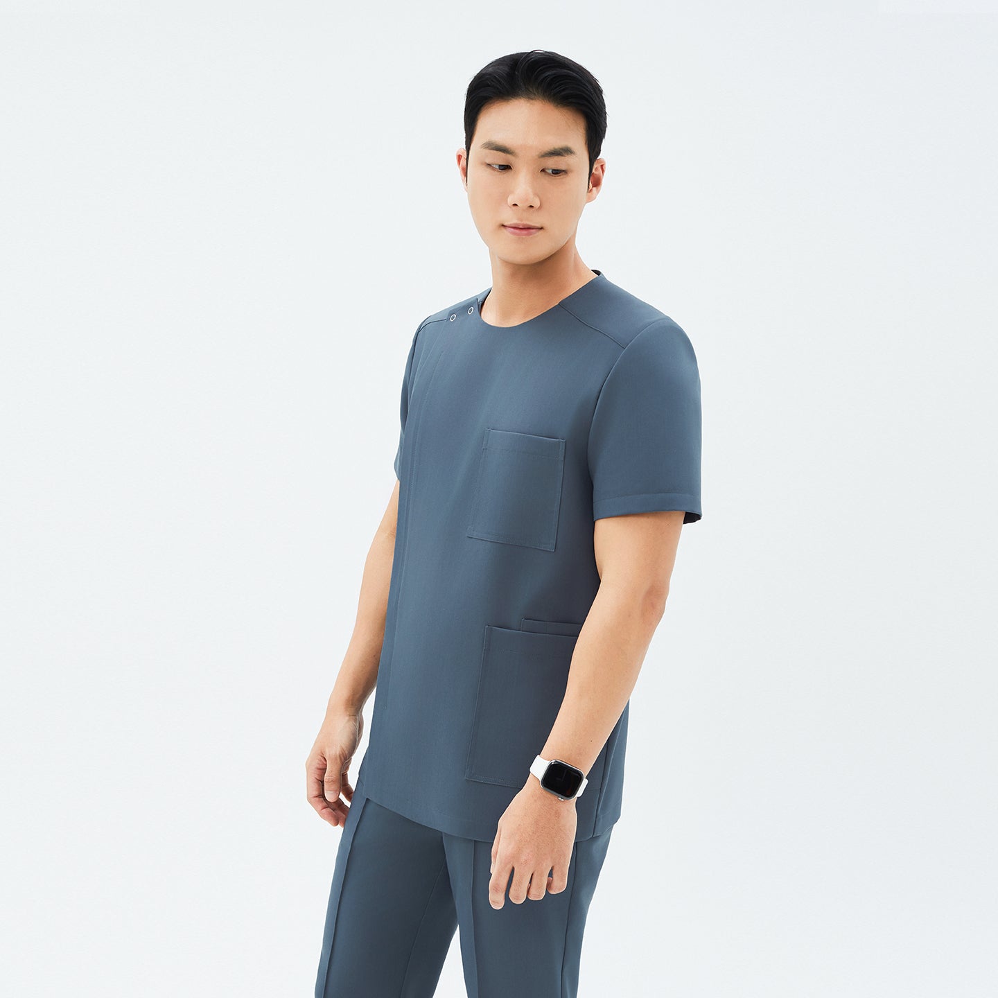 Image of Model wearing TUL DS-190 Haze Gray scrub top, emphasizing the snap closure near the shoulder and overall streamlined silhouette.