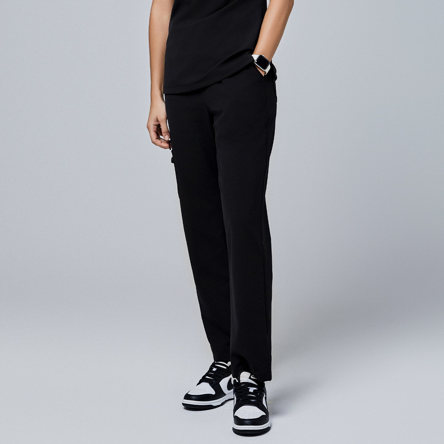 Image of Black utility scrub pants featuring a streamlined fit and side pockets, styled with black-and-white sneakers and a smartwatch,Jet Black