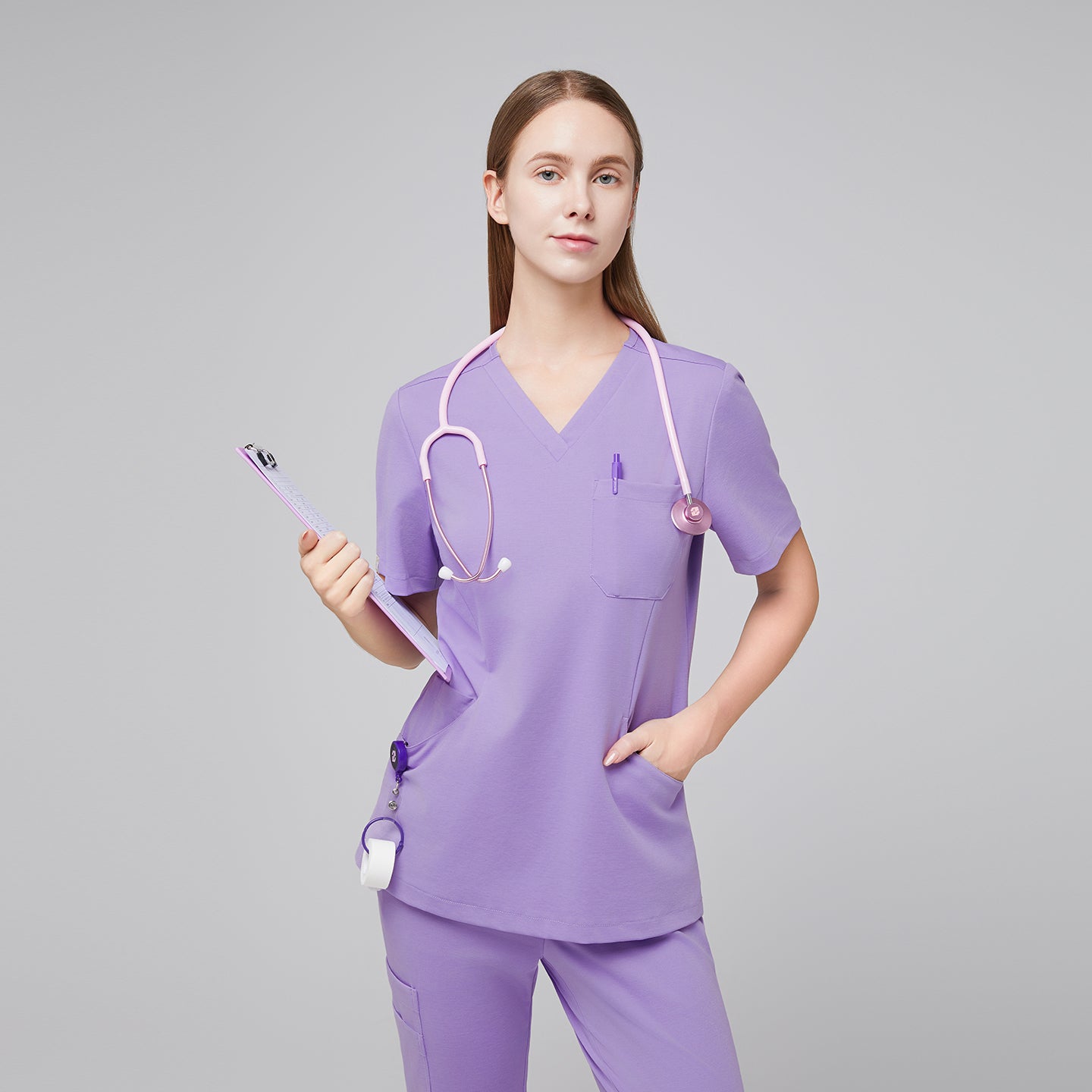 Image of Front view of a woman wearing a lavender scrub top and pants, accessorized with a pink stethoscope and holding a clipboard, highlighting a stylish and functional medical uniform,Lavender