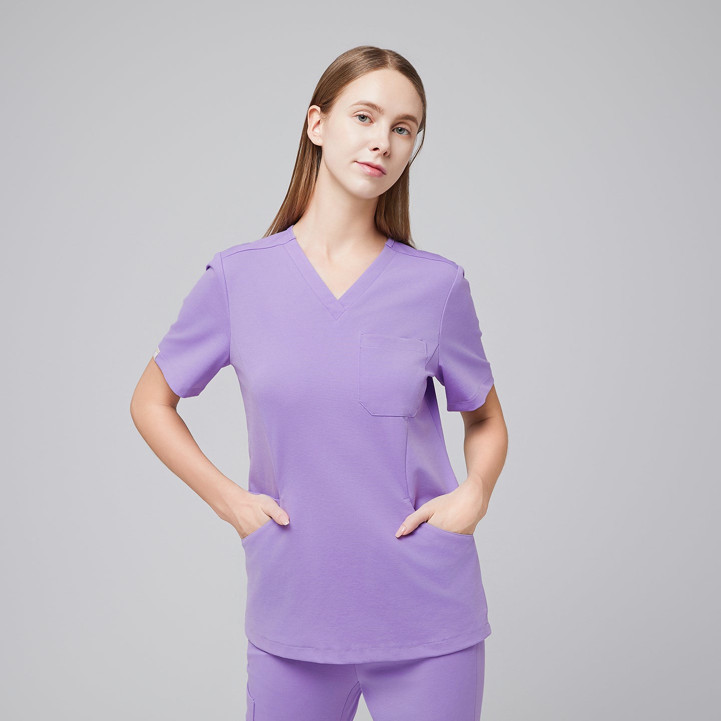 Image of Woman wearing a lavender scrub top and pants, standing with hands in pockets, showcasing the comfort and practicality of the medical uniform,Lavender