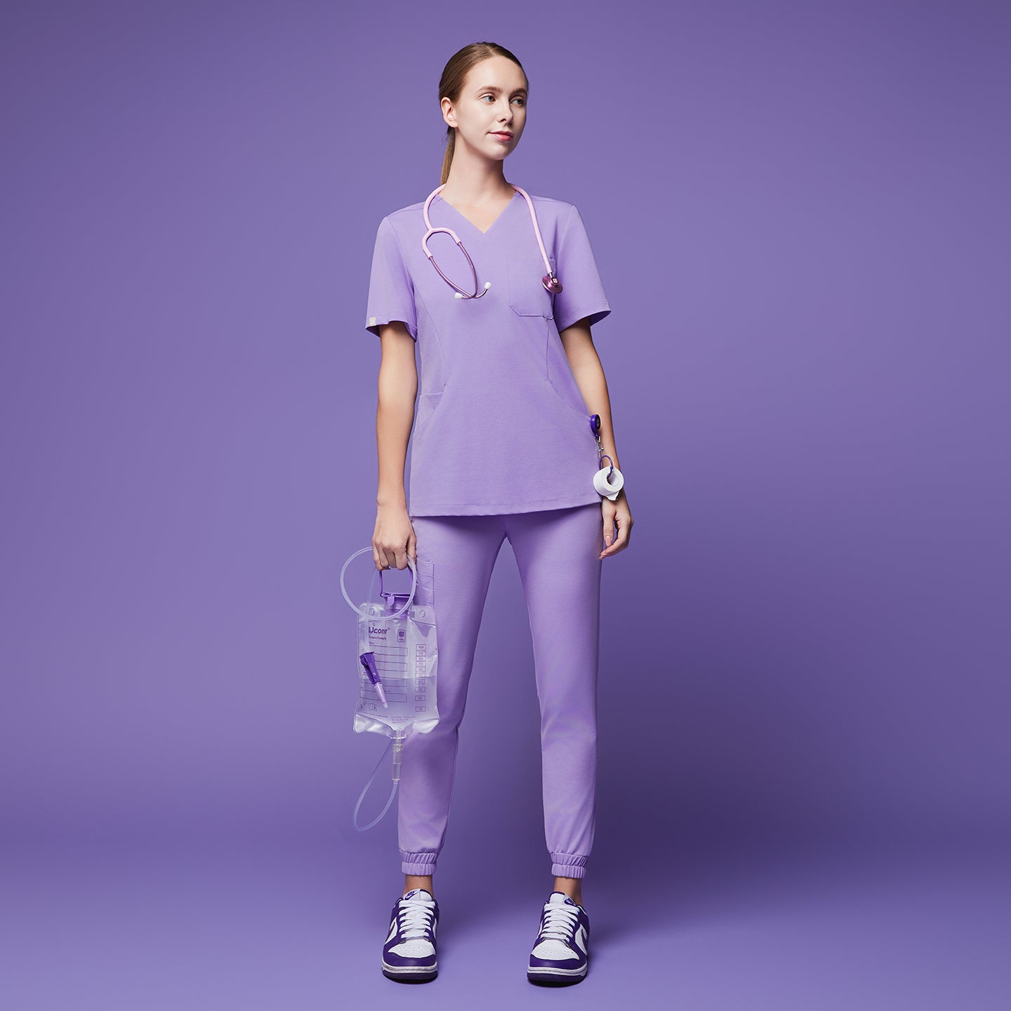 Medical professional in lavender scrubs, holding an IV bag and wearing a stethoscope, standing confidently against a matching lavender background,Lavender