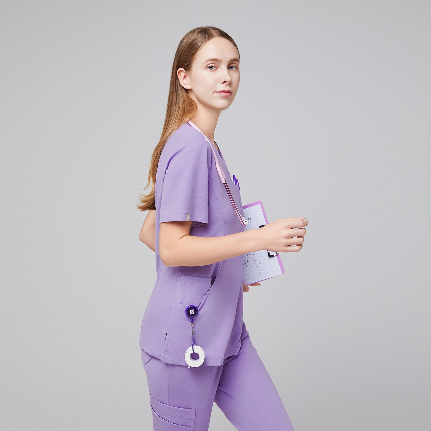Woman wearing a lavender scrub set, holding a clipboard and walking confidently, highlighting the professional and functional design of the uniform,Lavender
