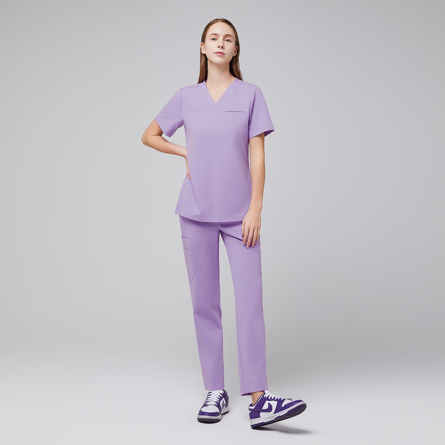 Image of Model wearing lavender V-neck scrub top and matching straight-leg scrub pants with purple sneakers,Lavender