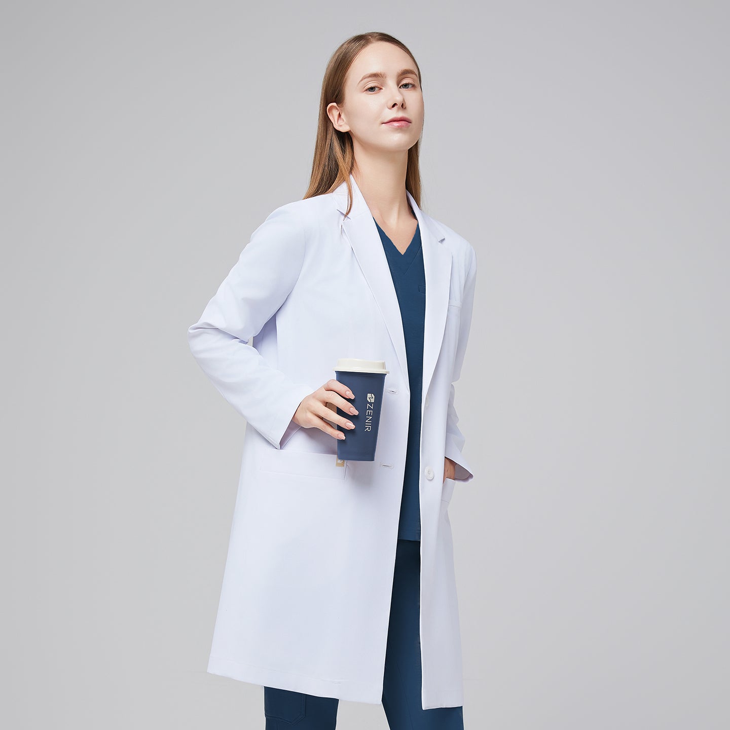 Image of A woman wearing a white long lab coat (LCW-10) over a Dark Blue Soft Stretch Scrub Top and Dark Blue Split Hem Scrub Pants, holding a coffee cup,White












