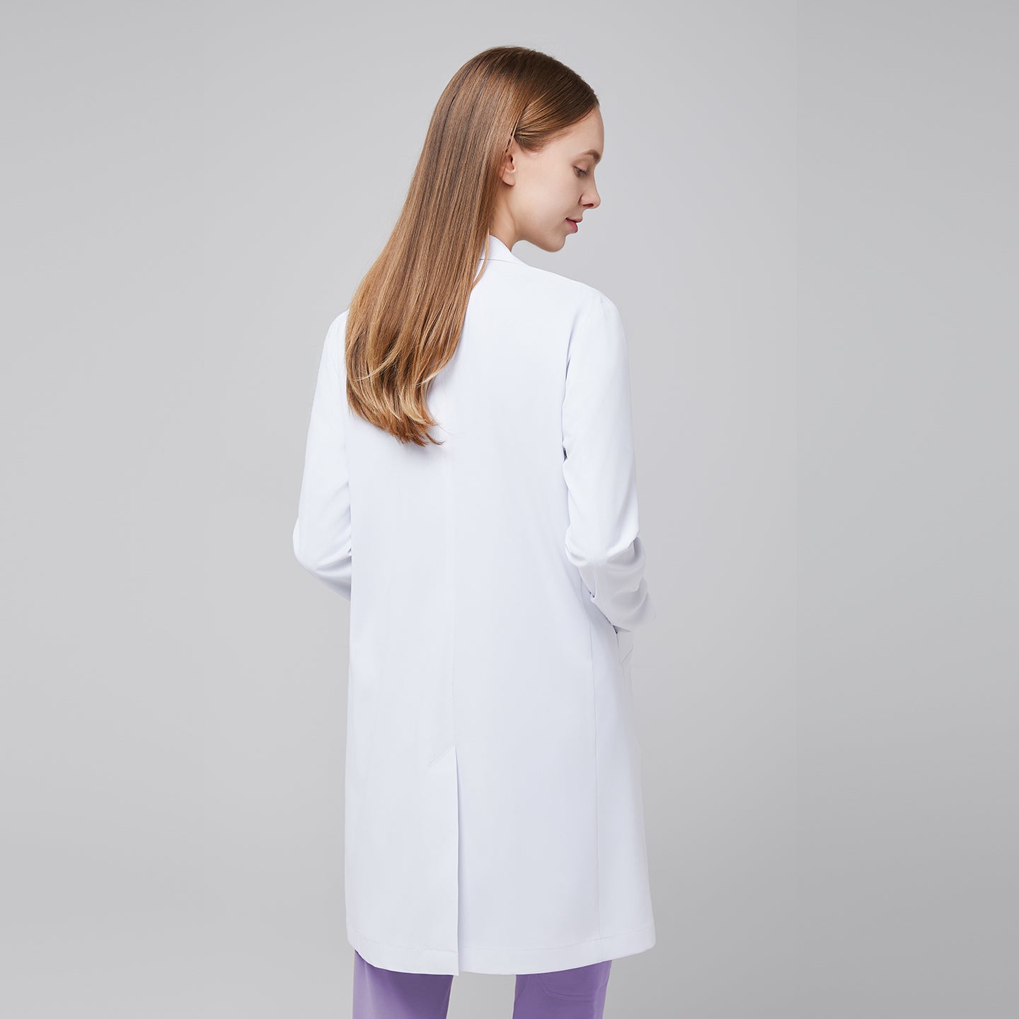 Back view of a woman wearing a white long lab coat (LCW-10) over a Lavender Soft Stretch Scrub Top and Lavender Straight Split Hem Scrub Pants,White
