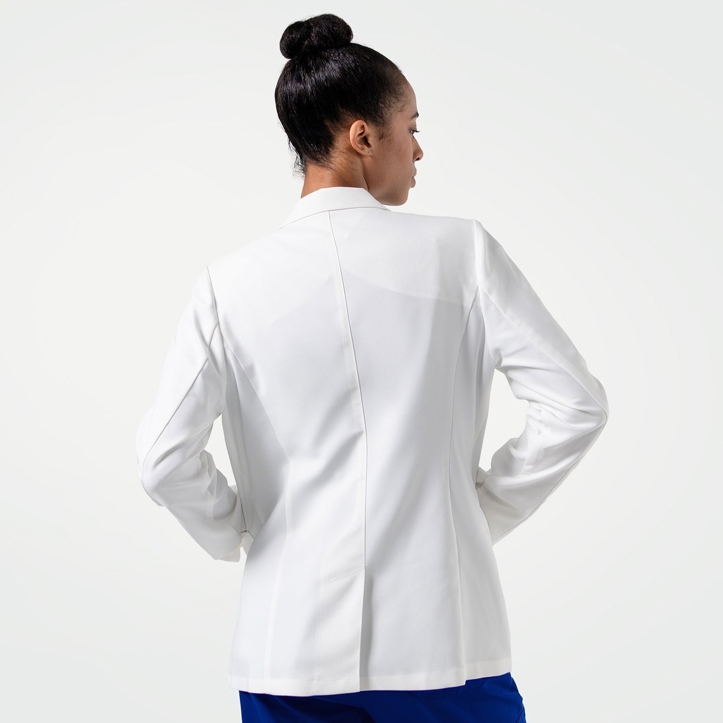 Image of Standing with hands on hips, the model displays the LCW-201 lab coat’s back view, showcasing the coat’s streamlined fit, crisp construction, and modern paneling that creates a sleek, confident profile.