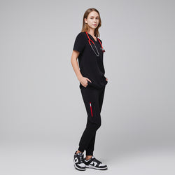 Image of Female healthcare professional wearing a midnight black scrub set with red accents and a red stethoscope, standing in a side pose with hands in pockets,Midnight Black