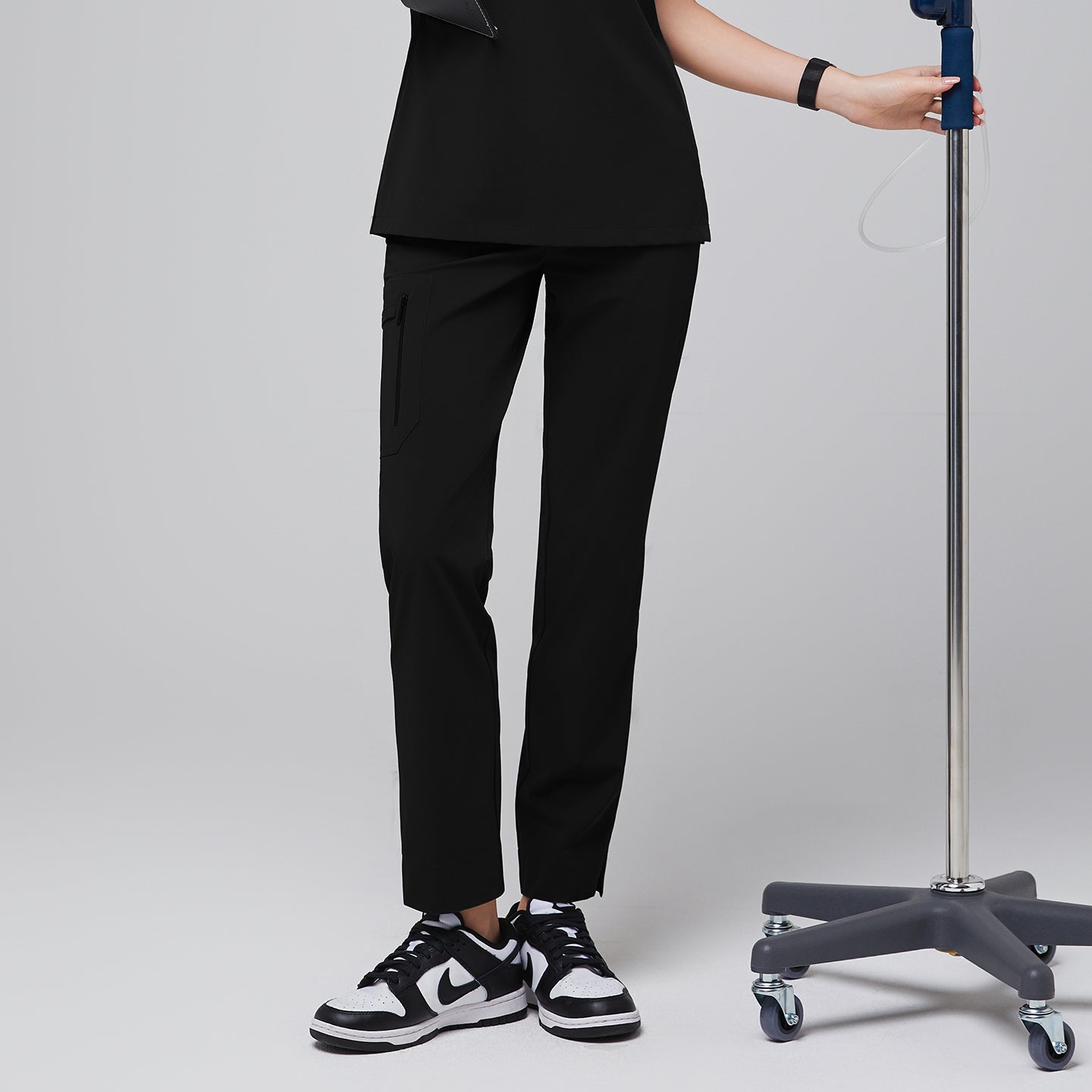 Image of Scrub pants with zipper pockets and split hem, paired with black and white sneakers, shown with a modern, functional design for healthcare professionals,Midnight Black