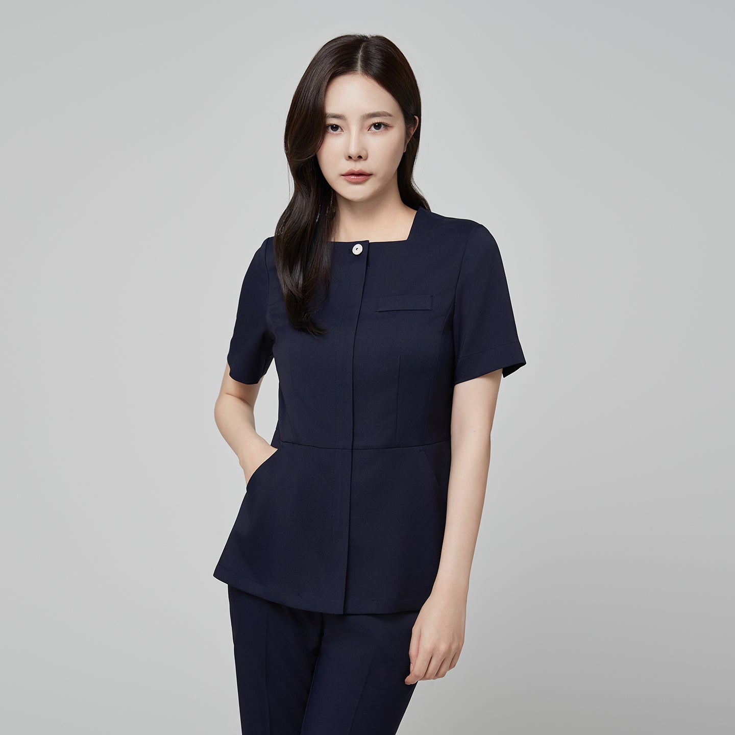 Image of Model wearing TUL NS-172 Women’s Modern Square Collar Scrub Top in Mir Navy, featuring a chest pocket and a contoured waist.