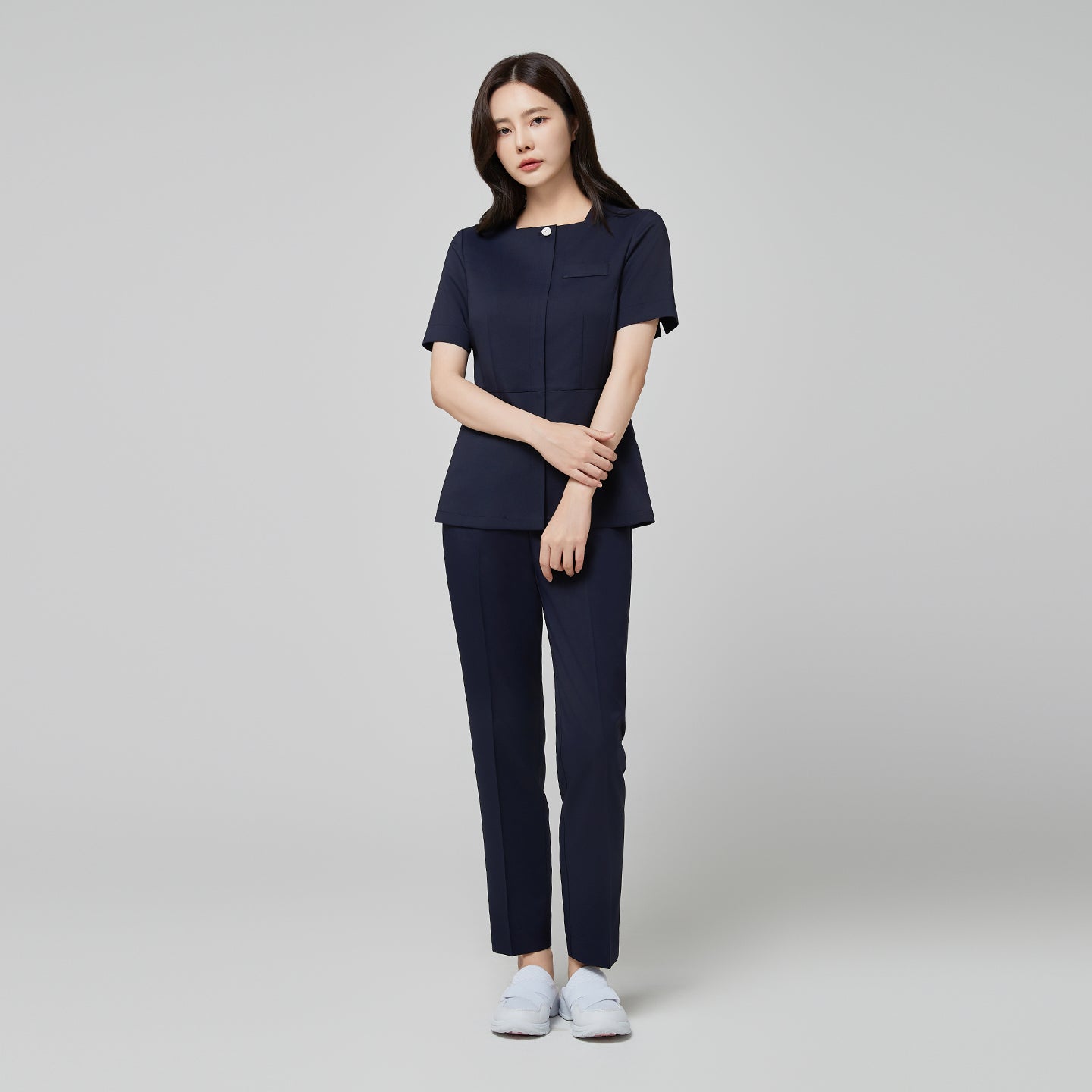 Image of Full-length shot of a model wearing the TUL NS-172 Women's Modern Square Collar Scrub Top in Mir Navy, paired with matching pants for a cohesive professional look.