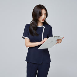 Image of Side angle of TUL NS-174 Women’s Check Gray Round Collar Scrub Top in Mir Navy, emphasizing the contrasting gray piping on the sleeves and neckline.