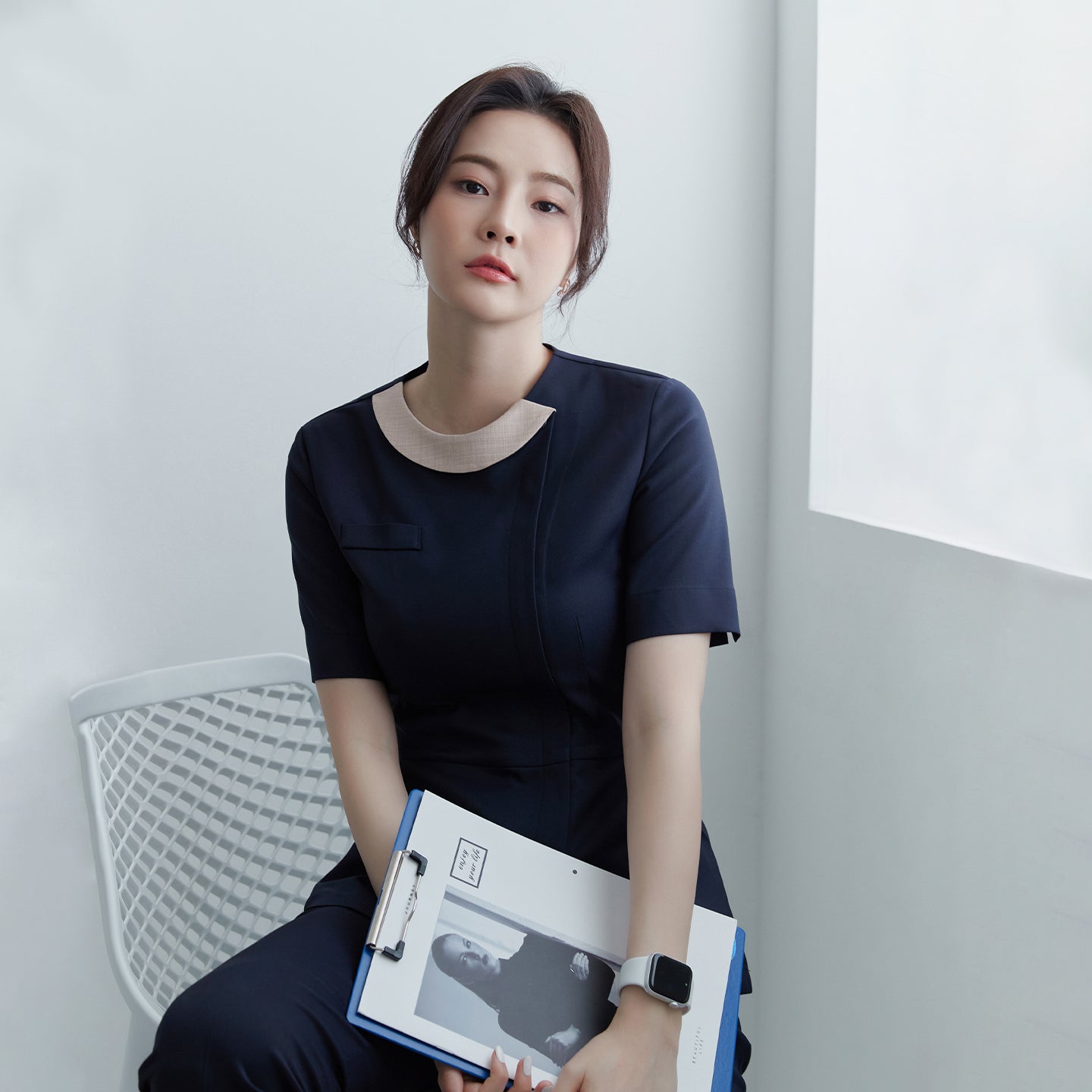 Image of A woman wearing a navy round-neck front zipper top, holding a clipboard with a monochrome photo,Mir Navy