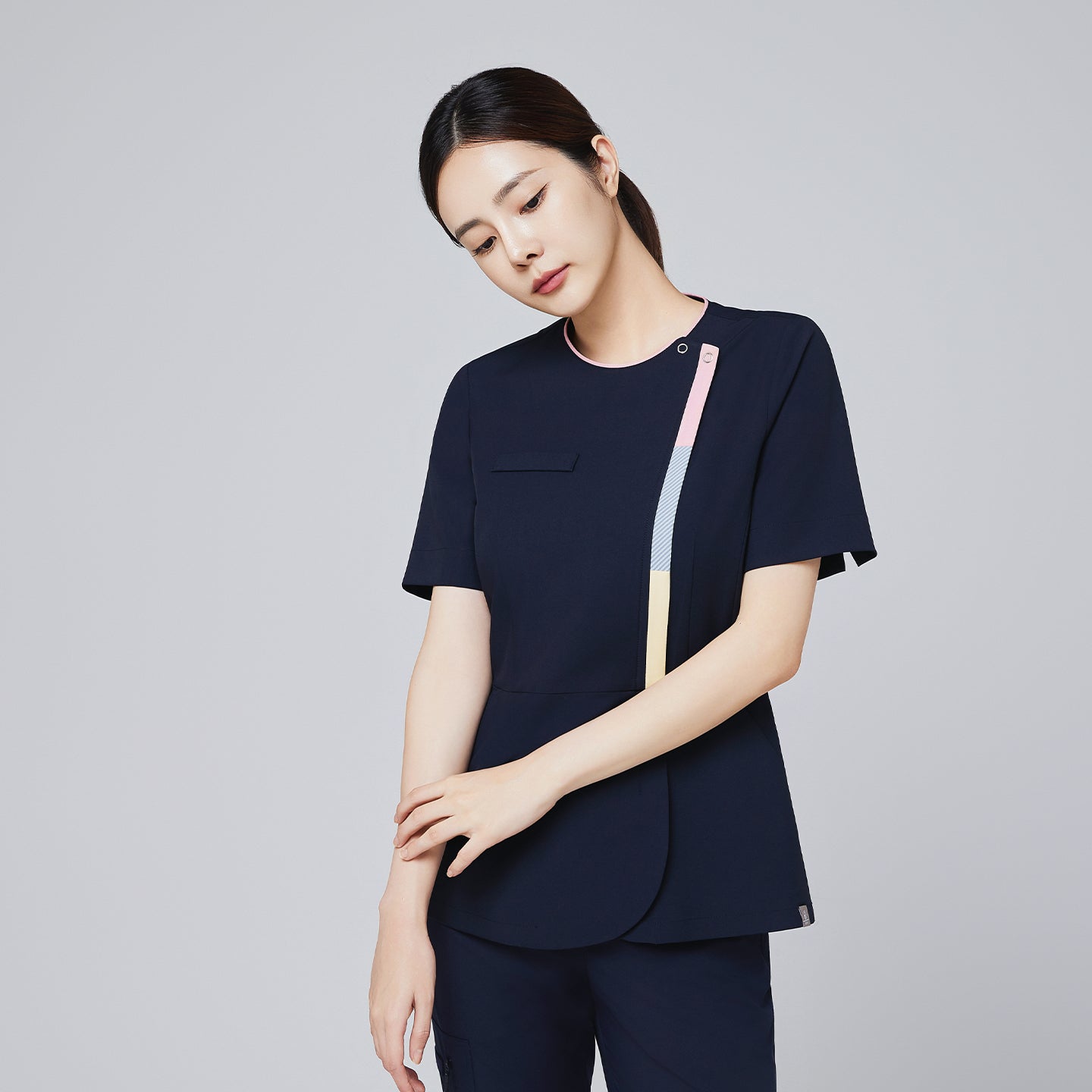 Image of Full-body view of a woman wearing a navy scrub set with gradient front zipper detail and sporty sneakers,Navy