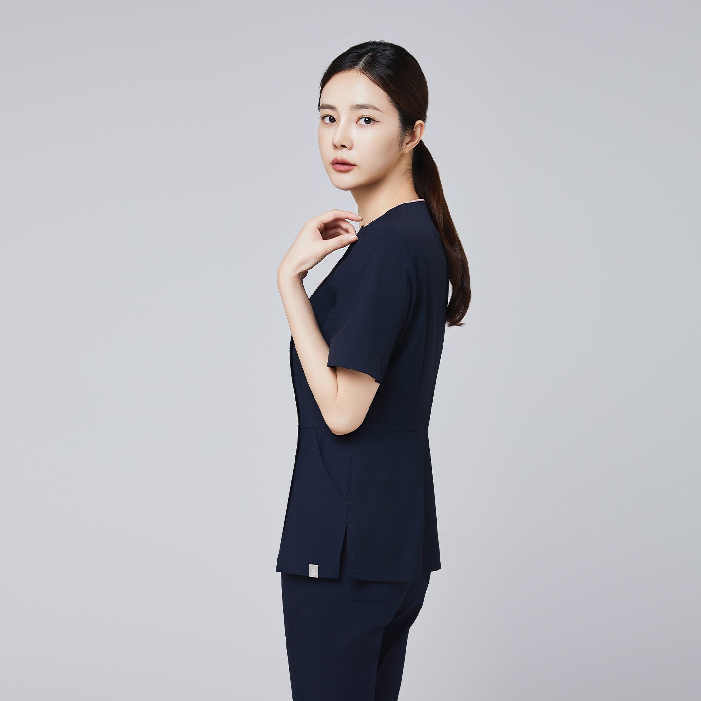 Image of Side profile of a woman wearing a navy scrub top with a tailored fit and gradient zipper detail, designed for professionals,Navy