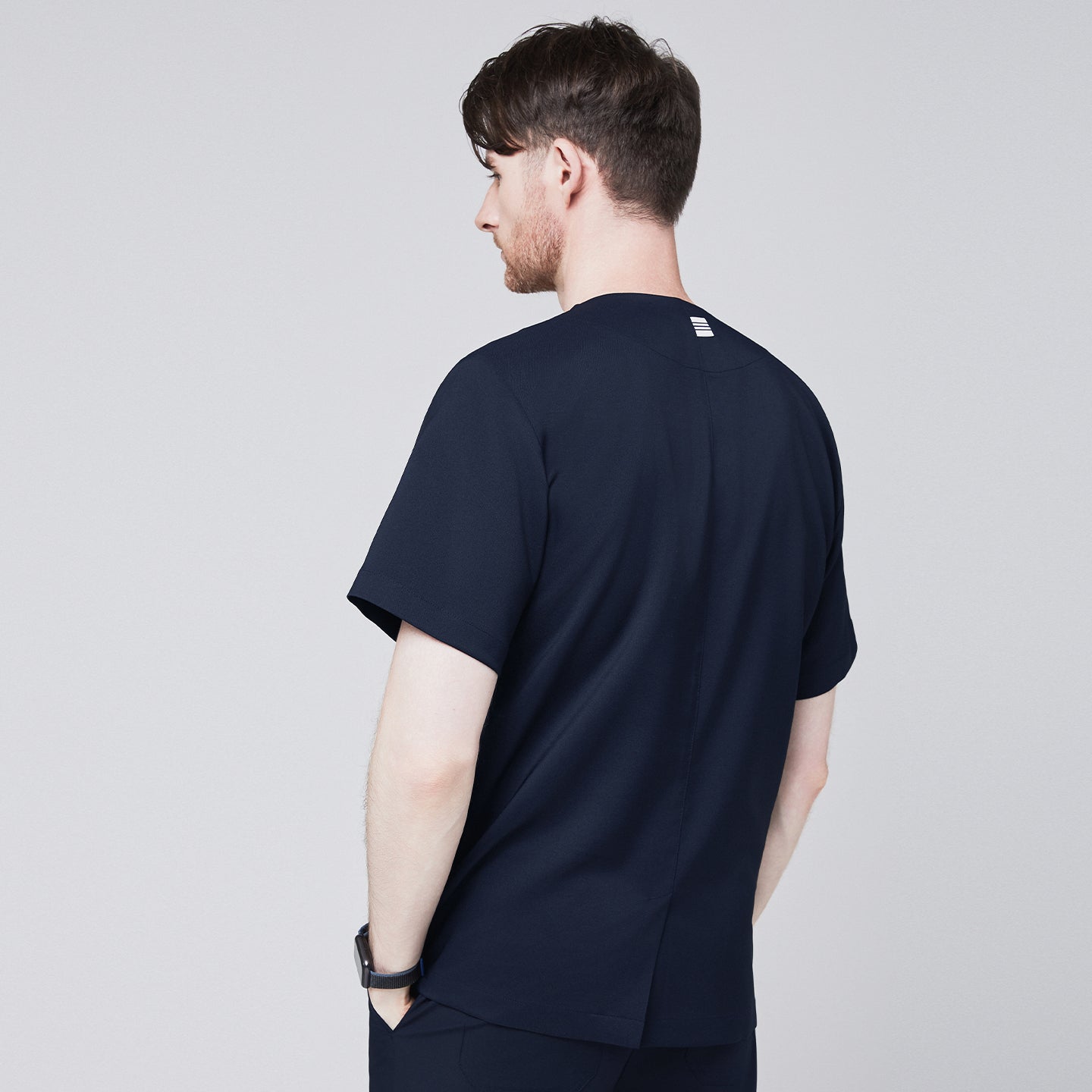 Image of Front view of a man wearing a navy scrub top with a front zipper, featuring a blue stethoscope draped around his neck,Navy