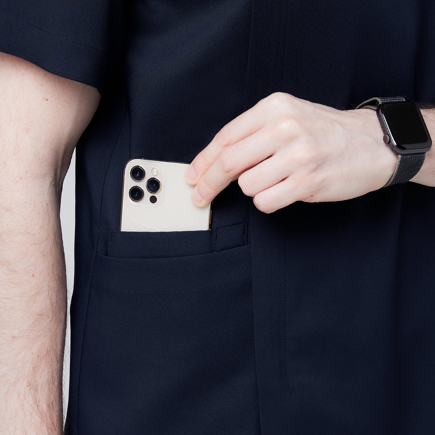 Image of Close-up of a man's hand placing a smartphone into the pocket of a navy scrub top, showcasing the functionality and convenience of the pocket design,Navy