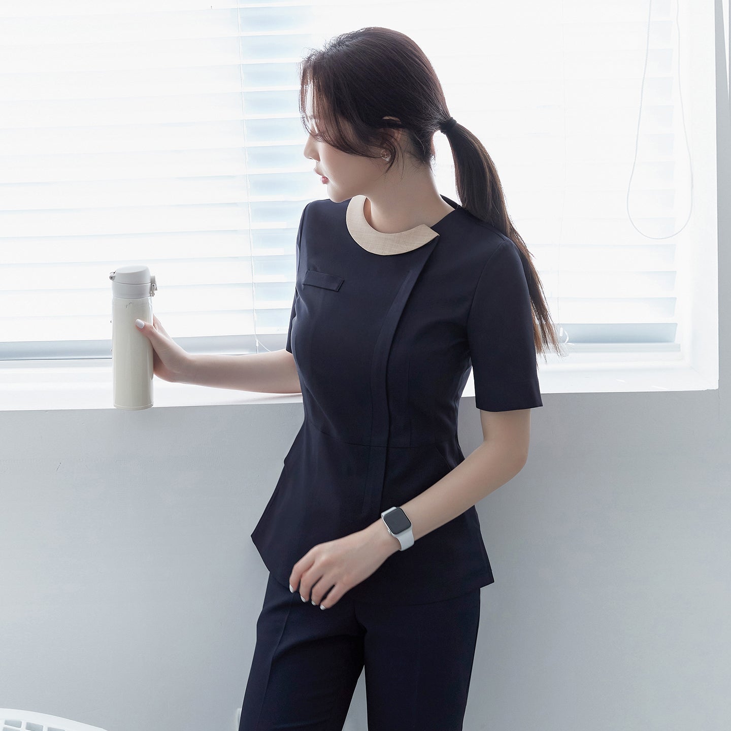 Image of Side profile of TUL NS-150 Women's Round Collar Front Zipper Scrub Top in Navy, featuring a contrasting light beige collar and a fitted waist.