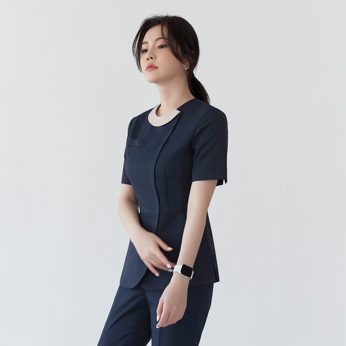 Image of Model wearing TUL NS-150 Women's Round Collar Front Zipper Scrub Top in Navy, featuring a sleek silhouette and contrasting collar detail.