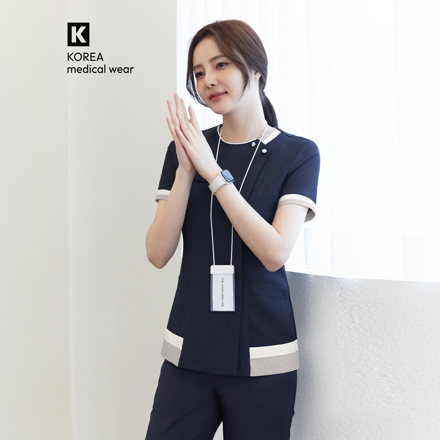 Image of Model wearing TUL NS-168 Women's Check Zipper Scrub Top in Navy, featuring contrasting light trim on the sleeves and waist.