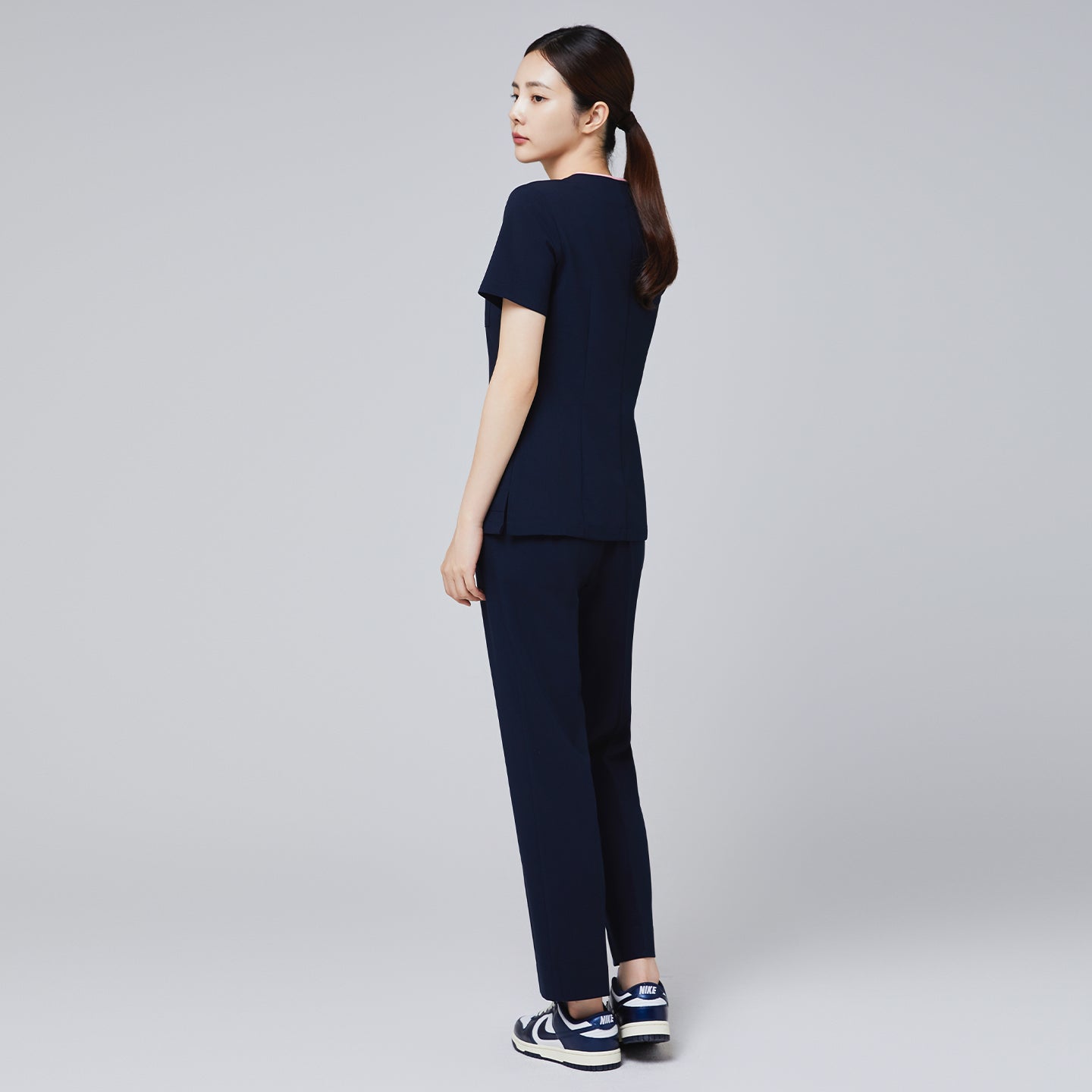 Image of Back of Women's Pocket Banding Pants in Navy with matching scrub top and matching navy sneakers,Navy