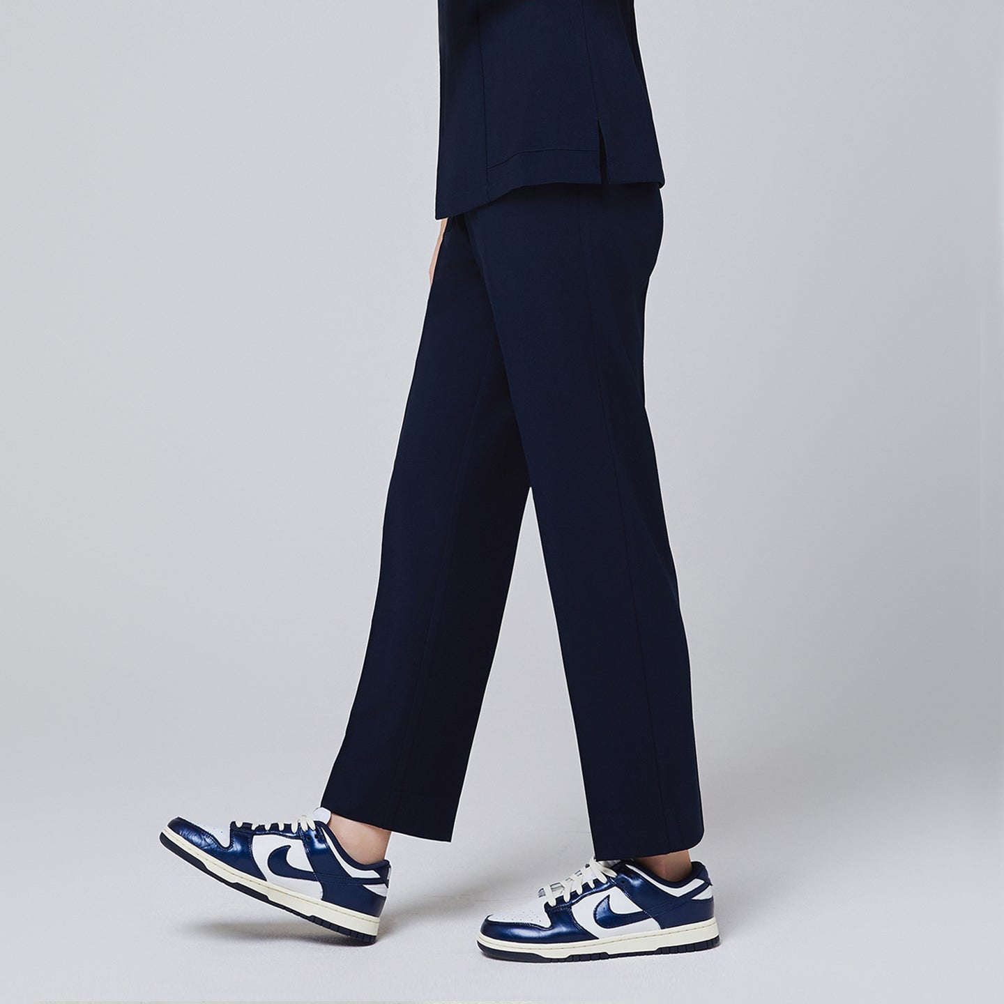 Image of Side of women's Pocket Banding Pants in Navy with matching scrub top and matching navy sneakers,Navy