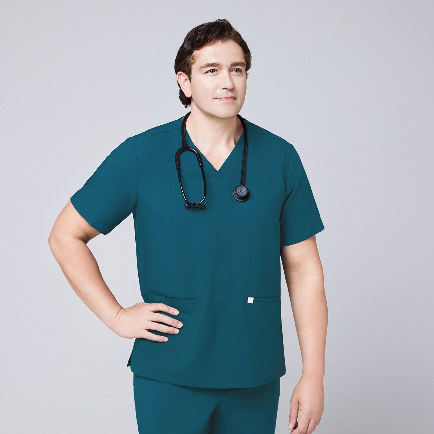 Image of Ocean teal scrub top with two pockets and matching ocean teal straight scrub pants with black stethoscope around neck and hands on waist,Ocean teal
