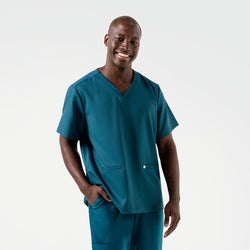 Image of Model smiling while wearing the Ocean Teal Double Pocket Scrub Top with one hand in the pocket.
