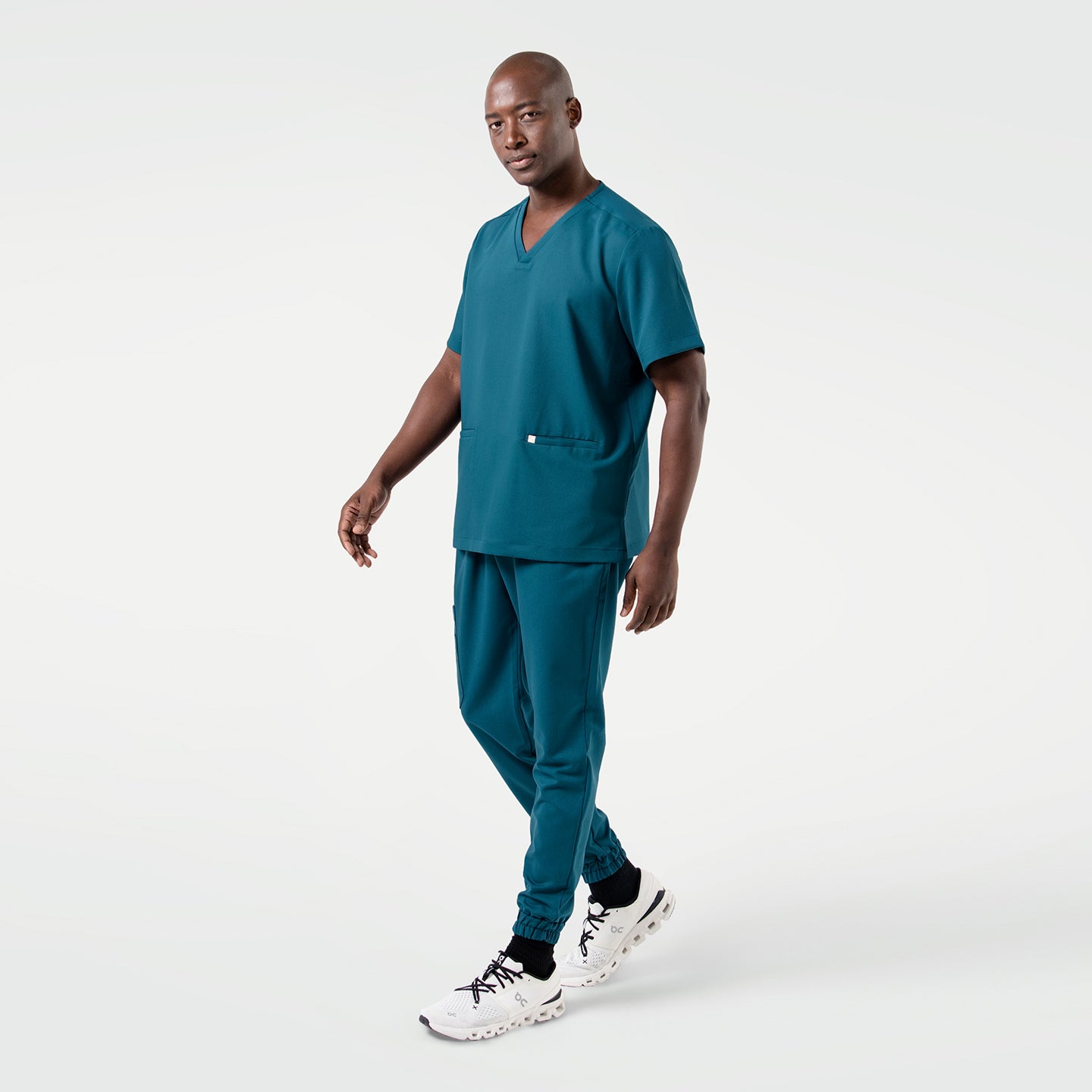 The Ocean Teal Double Pocket Scrub Top features a sleek silhouette with a relaxed yet polished side profile.