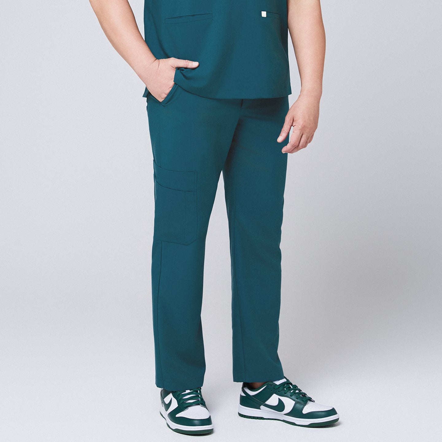 Image of Ocean teal straight scrub pants with side pockets and matching ocean teal scrub top, with a hand in pocket,Ocean teal