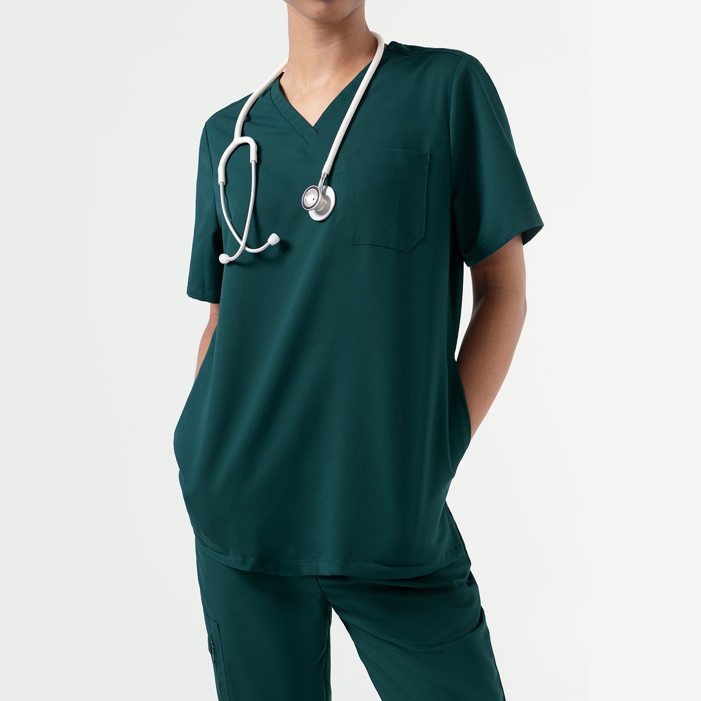 Image of Close-up of the Pine Green 3-Pocket Scrub Top, shown with a stethoscope draped around the neck and hands in the pockets, highlighting the clean V-neck and single chest pocket design.